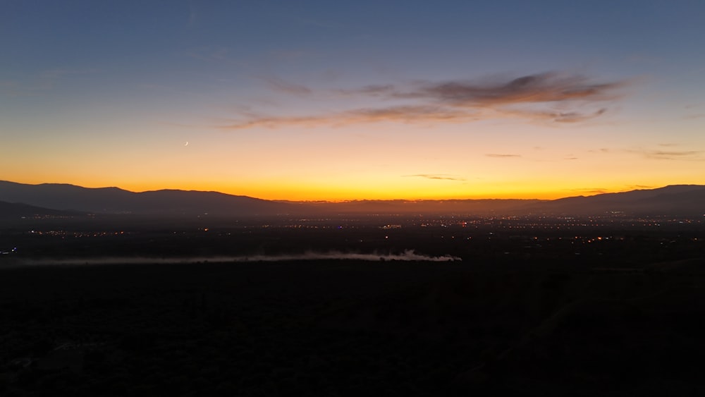 the sun is setting over the mountains in the distance