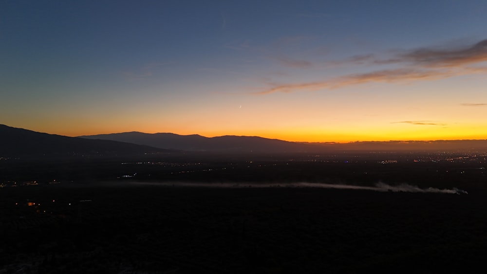 In der Ferne geht die Sonne über den Bergen unter