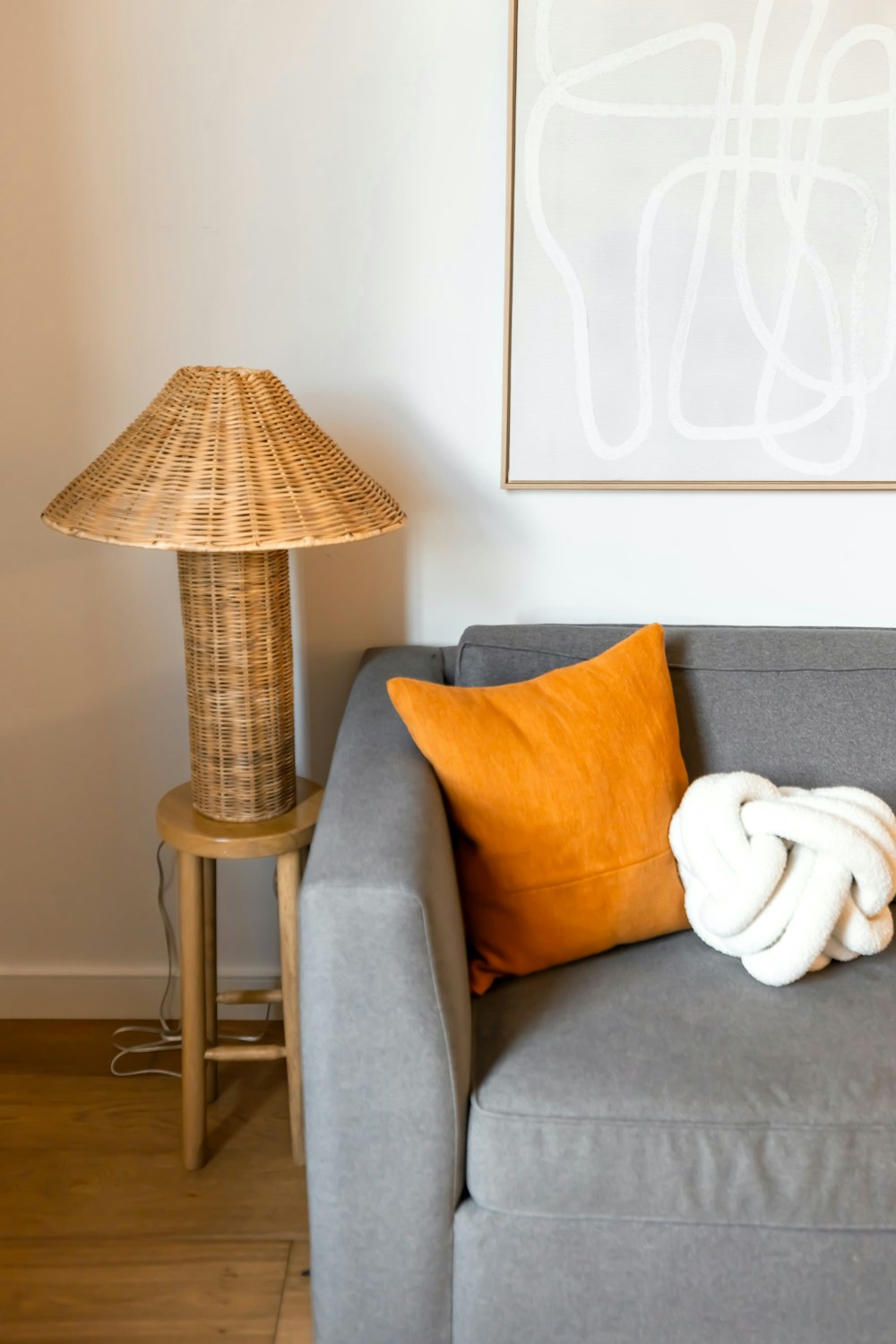 a gray couch with orange pillows and a lamp