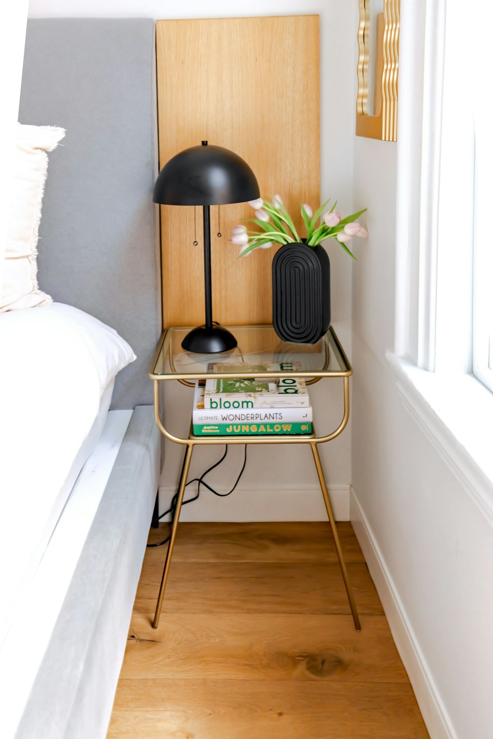 a nightstand with a lamp and books on it