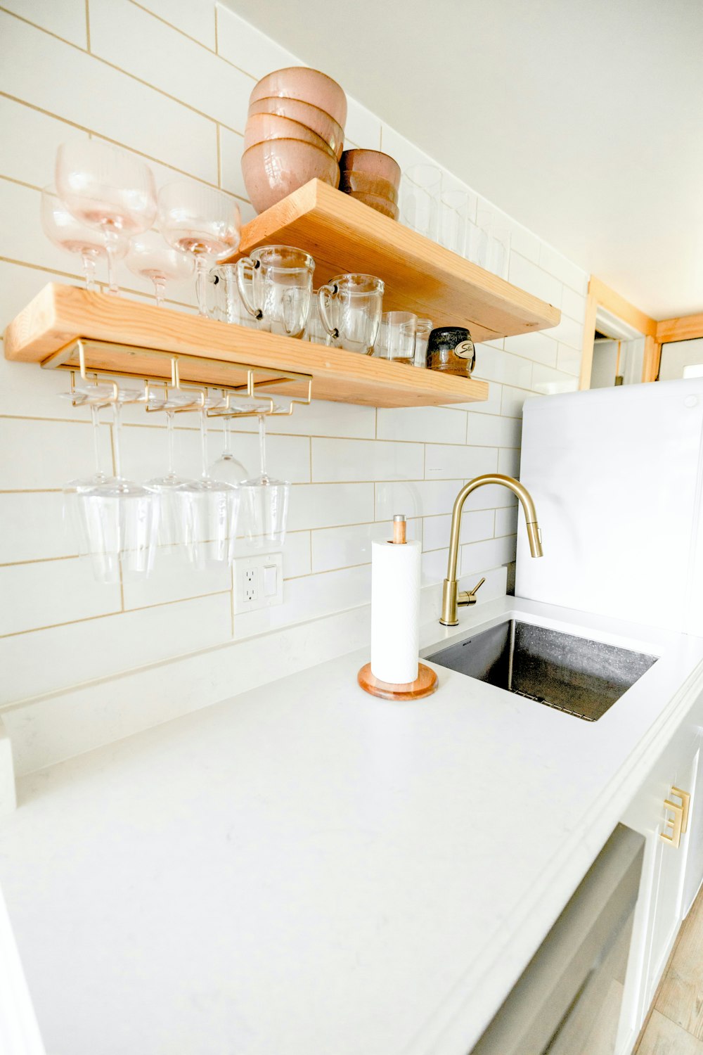 uma cozinha com bancada branca e prateleiras de madeira