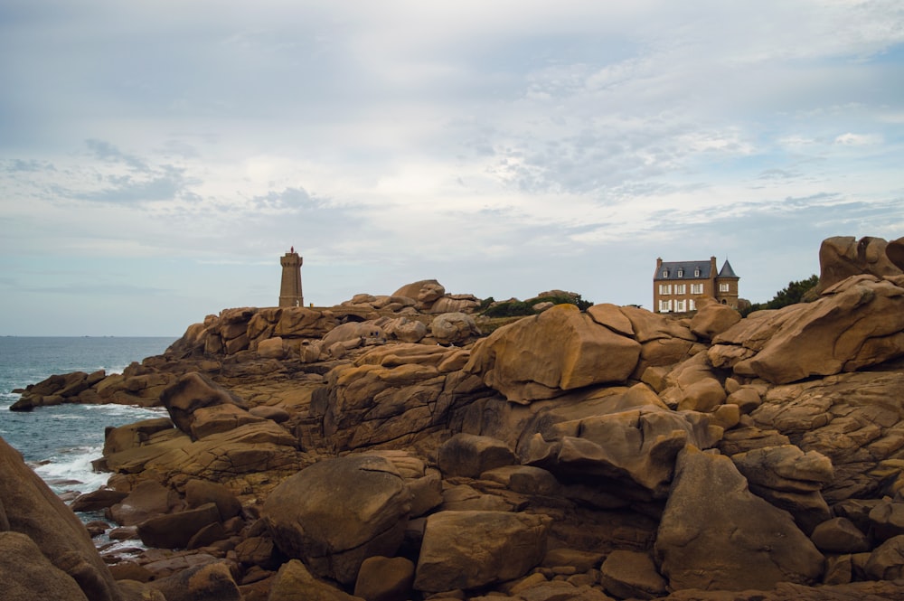 a house sitting on top of a rocky cliff next to the ocean