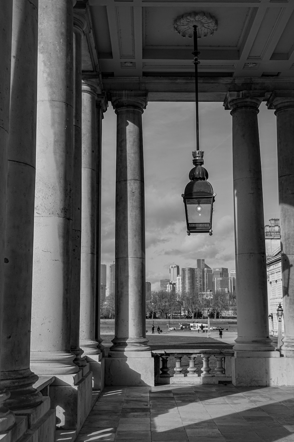 a black and white photo of a lamp hanging from a building