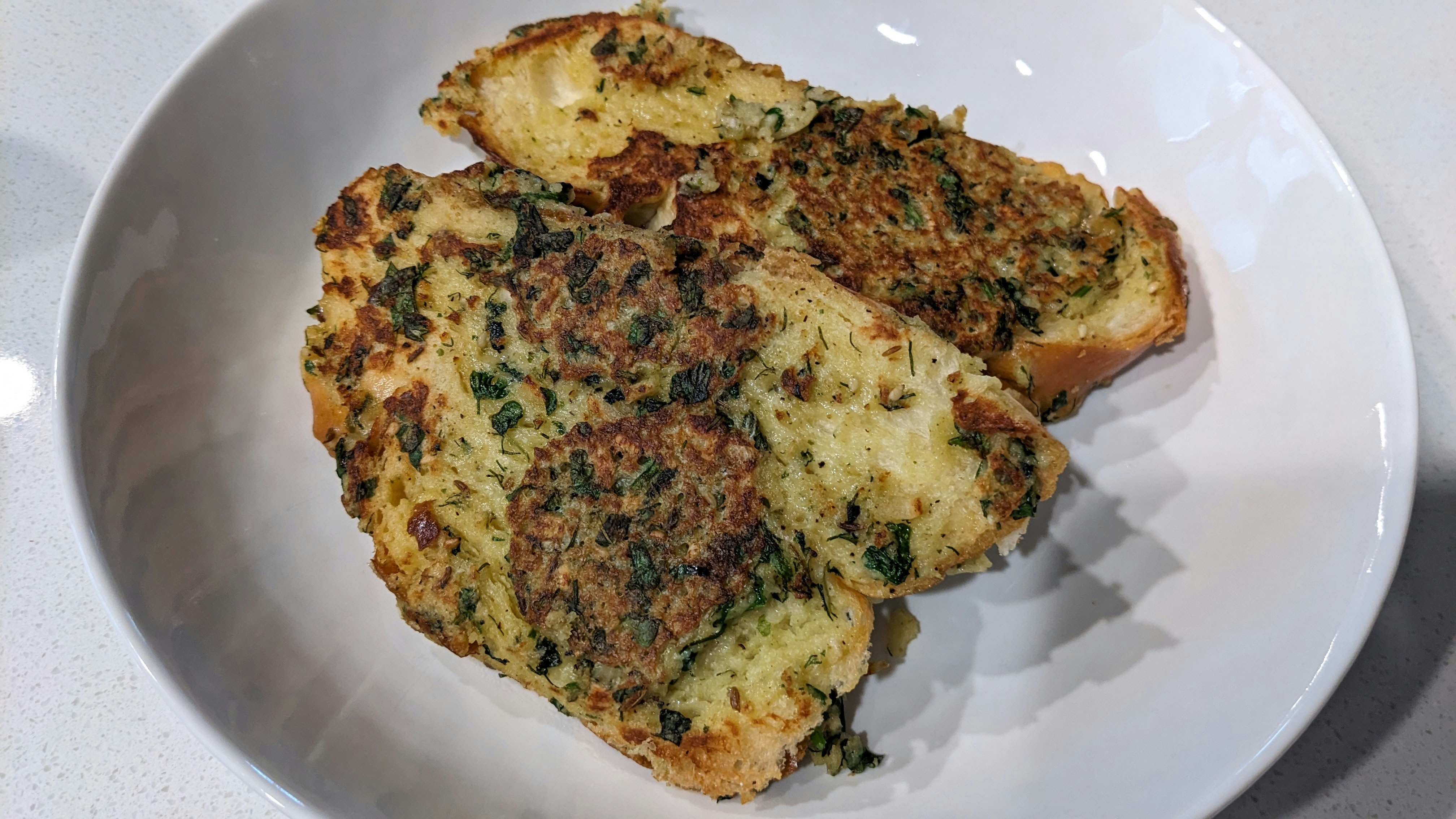 Garlic bread slices with herbs on dark wooden board, low-key lighting