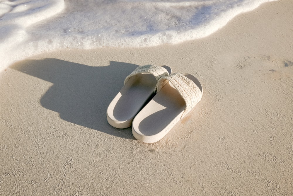 a pair of slippers sitting on top of a sandy beach