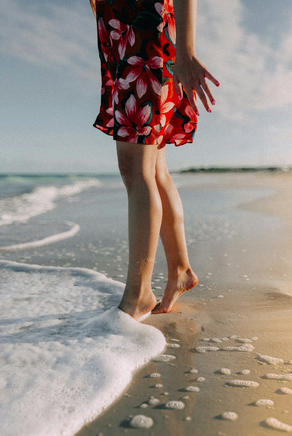 a woman walking along a beach next to the ocean