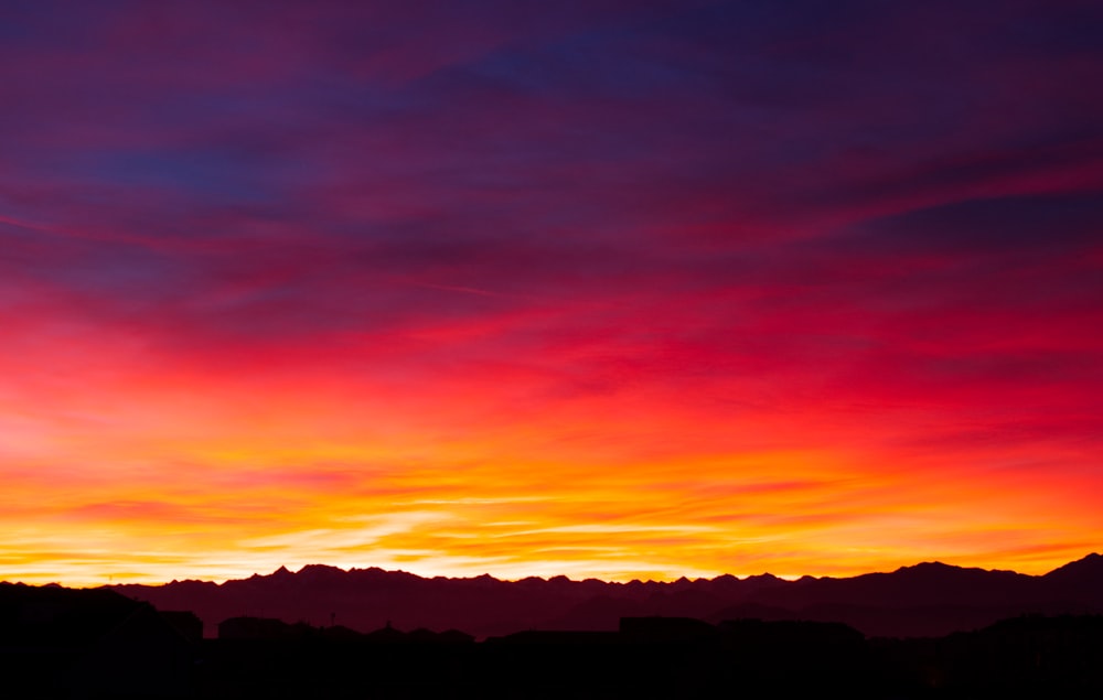 a colorful sunset with clouds and mountains in the background