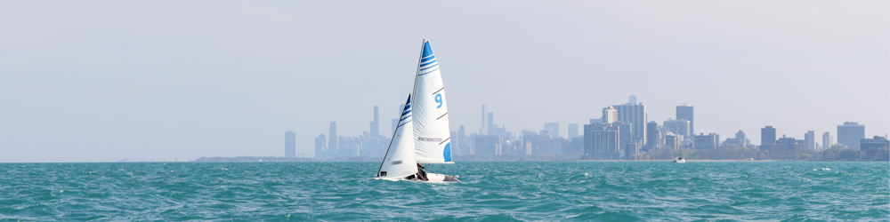 Un velero en medio del océano con una ciudad al fondo