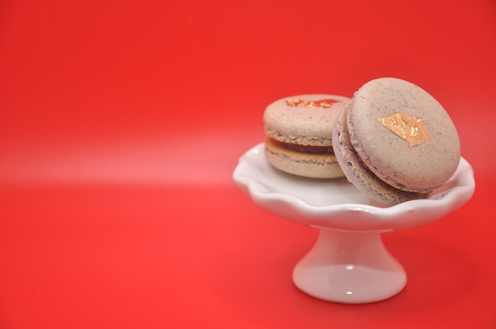 two macaroons sitting on a white plate on a red background