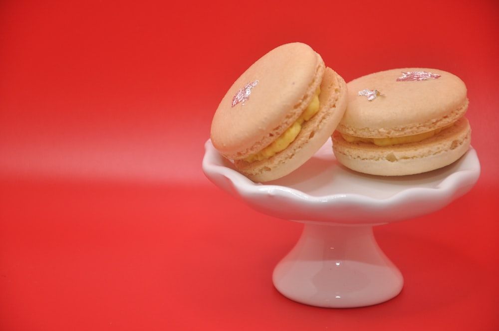 a white plate topped with two macaroons on top of a red table