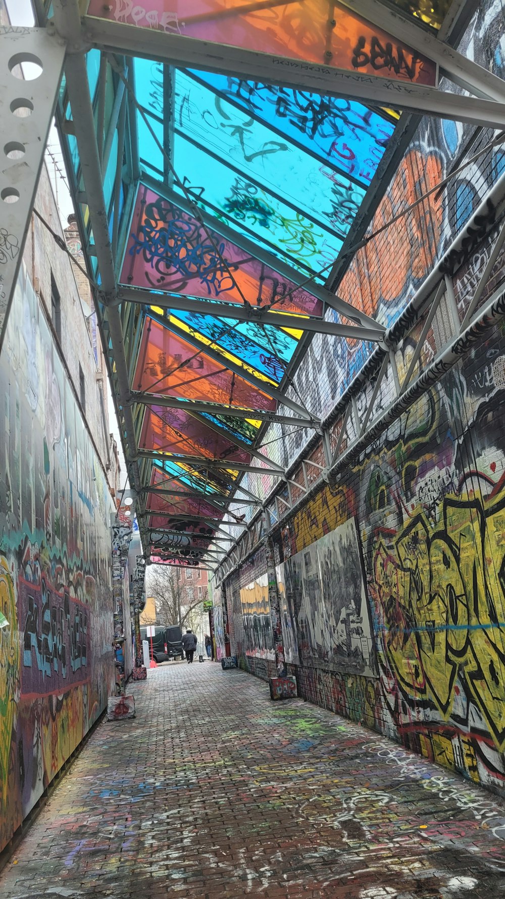 a walkway with graffiti on the walls and a skylight