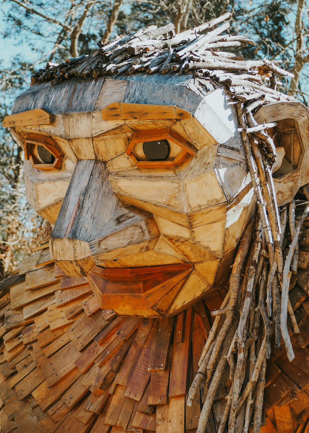 a wooden sculpture of a woman's face with branches on her head