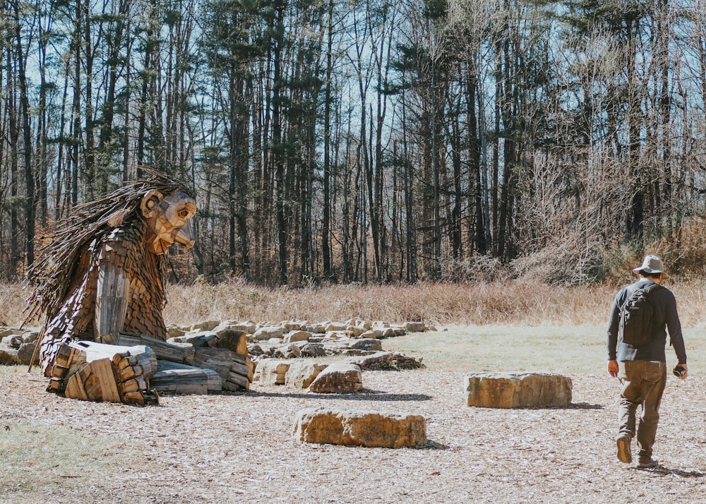 a man standing in a field next to a pile of logs