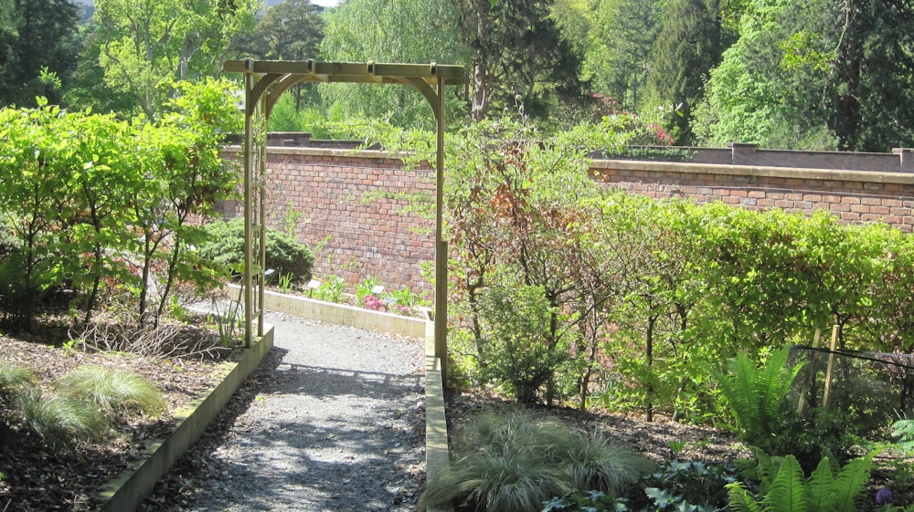 a garden with a stone path leading to a brick wall