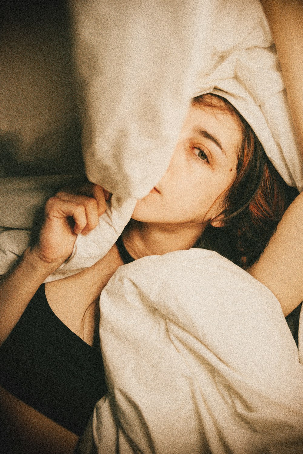 a woman laying in bed under a white blanket
