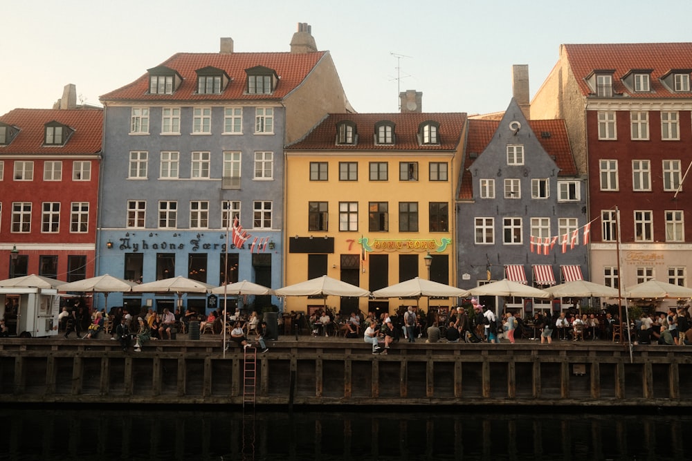 a group of people standing on a pier next to buildings