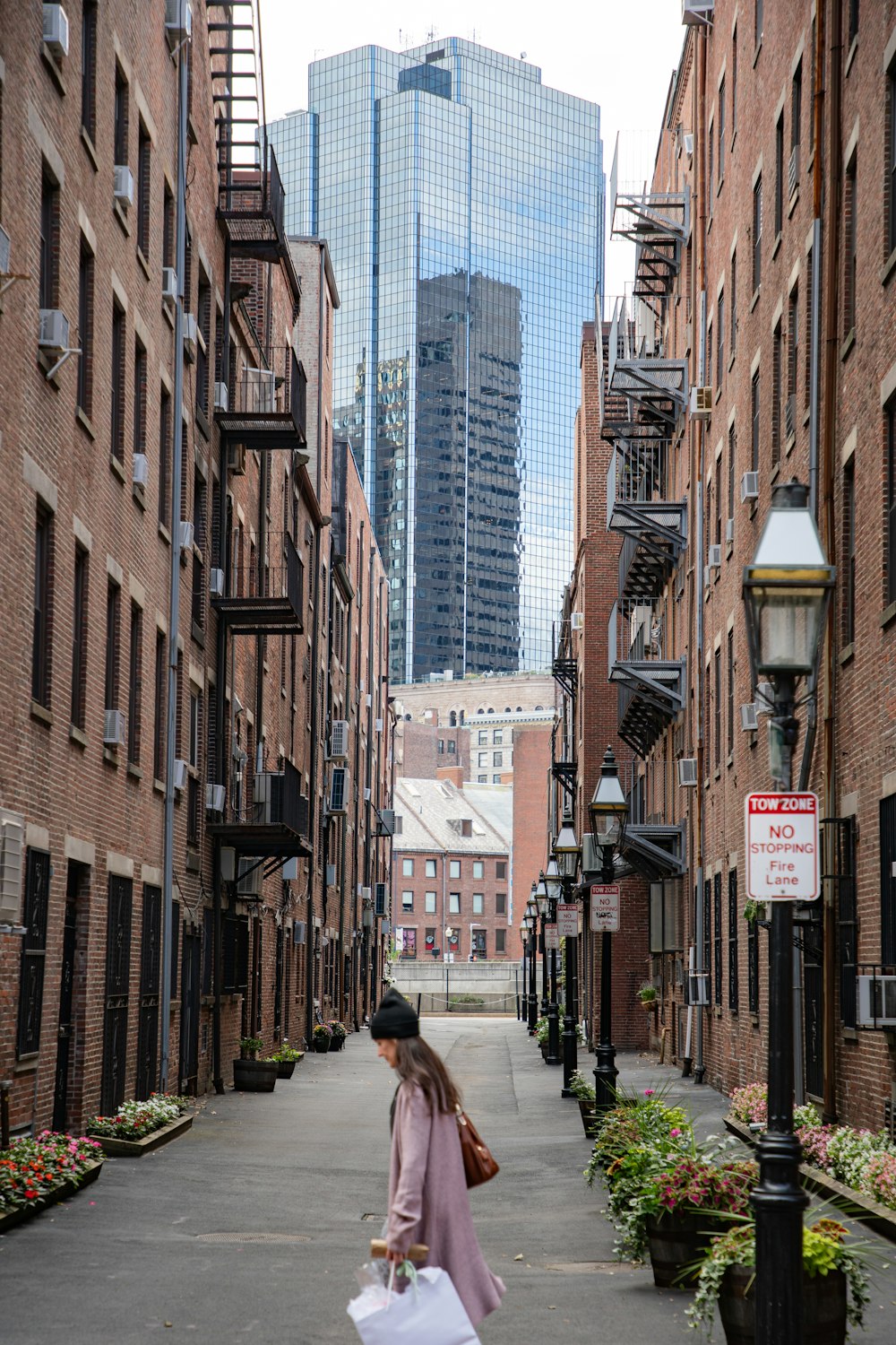 a woman walking down a street holding a bag