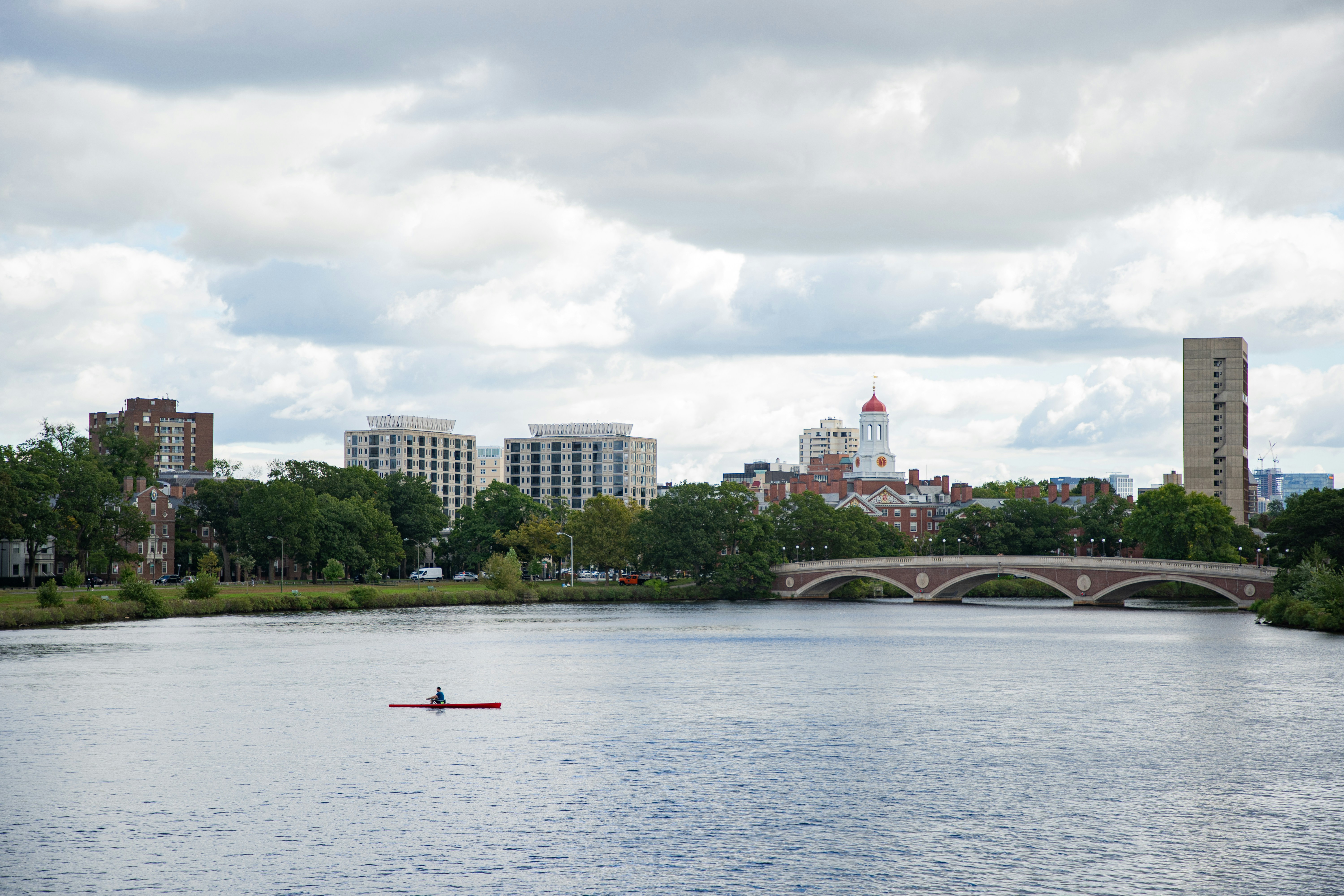 a person in a boat on a river with a bridge in the background