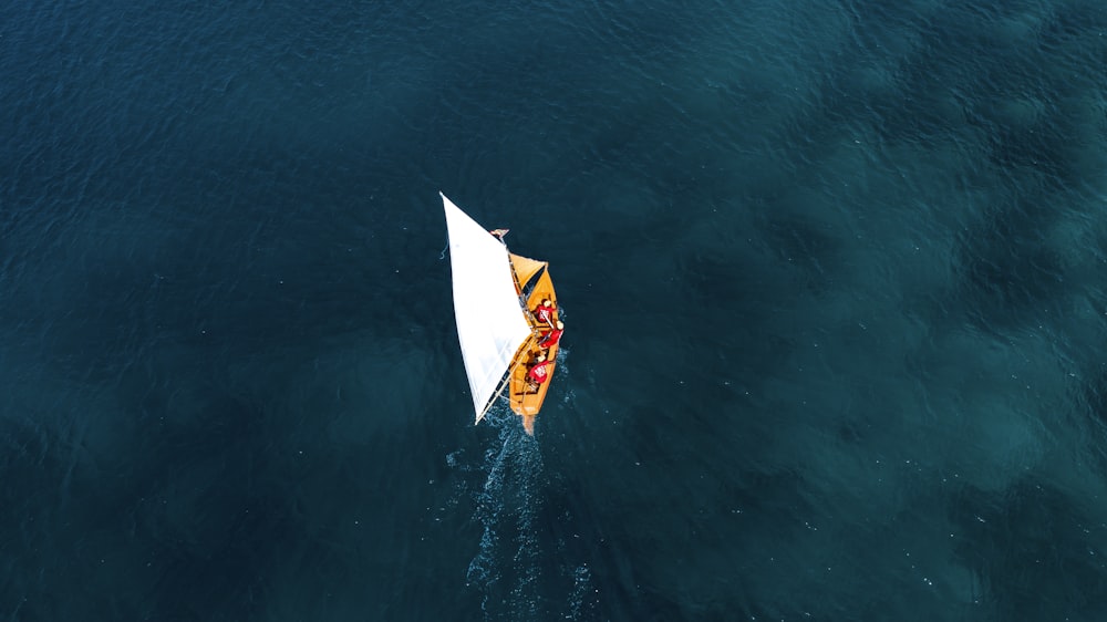 a yellow and white boat floating on top of a body of water