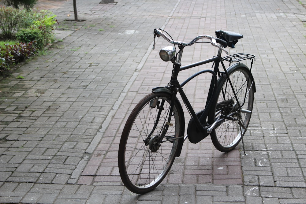 a black bicycle parked on a brick sidewalk