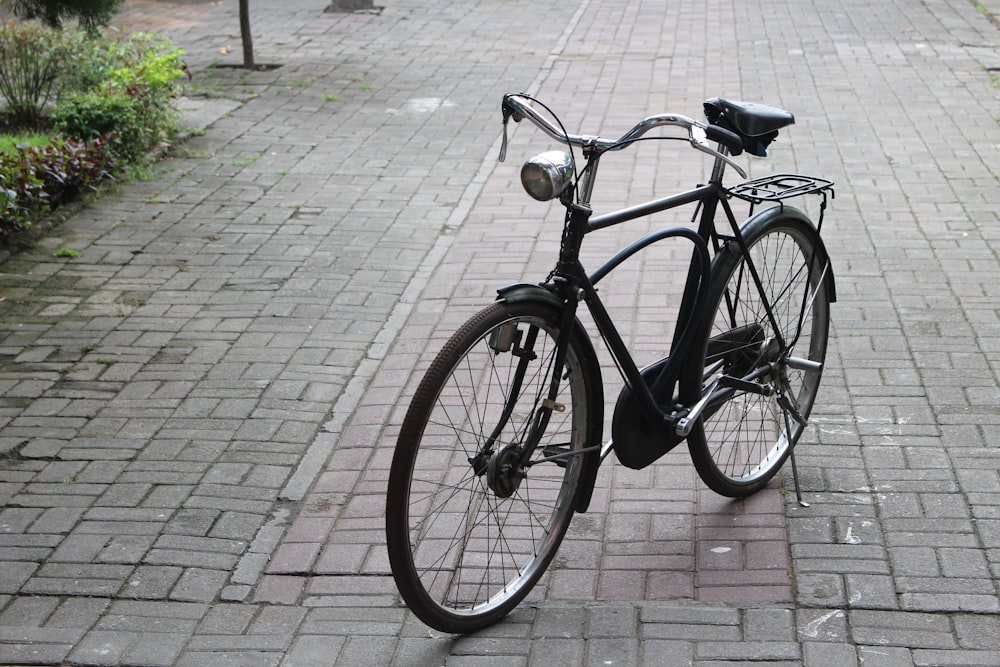 una bicicleta negra estacionada en una acera de ladrillos