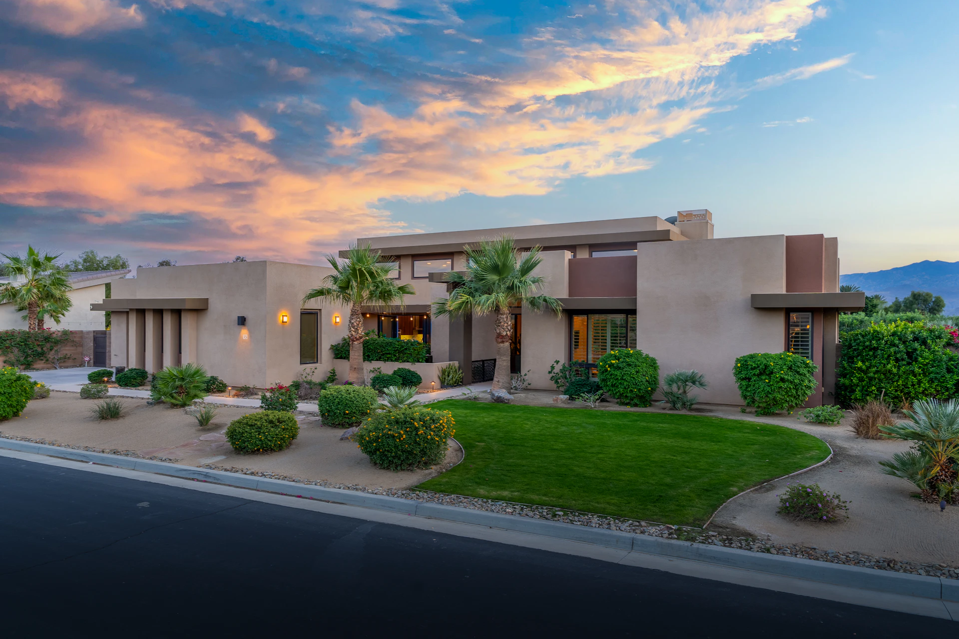 Desert-modern home with a palm tree and landscaped yard at sunset