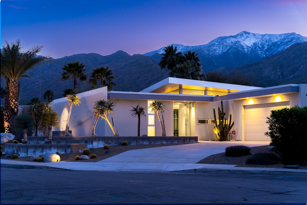 a white house with palm trees and mountains in the background