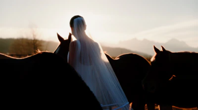 a woman in a wedding dress standing between two horses