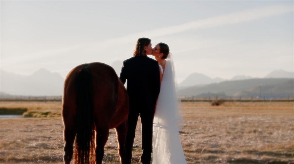 une mariée et un marié debout à côté d’un cheval