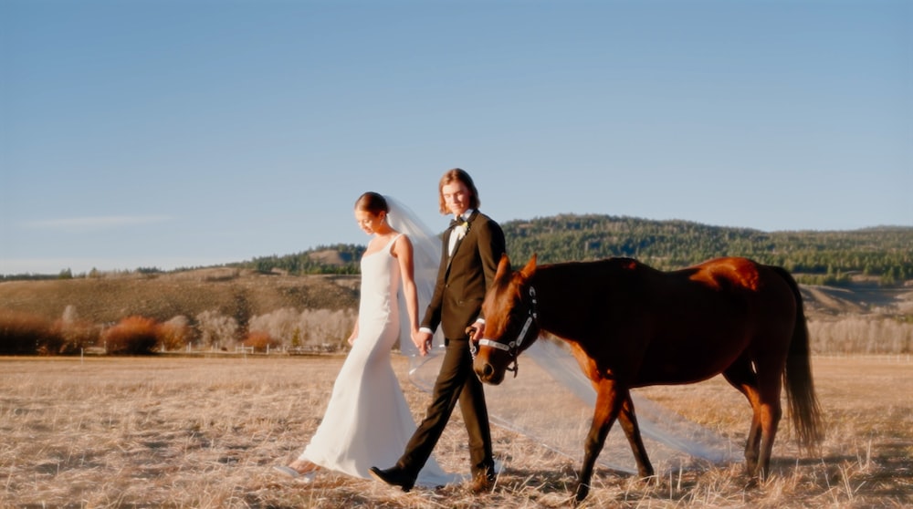 a bride and groom are walking with a horse