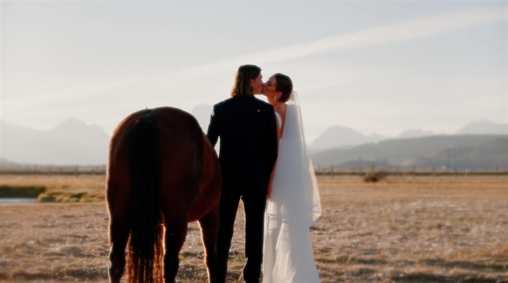 a bride and groom standing next to a horse