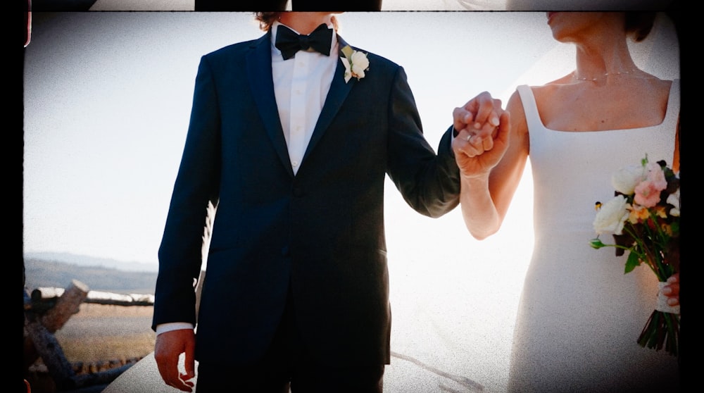 a man and a woman in formal wear holding hands