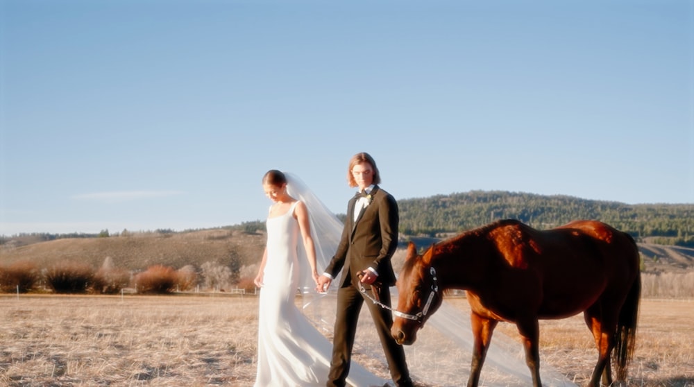 a bride and groom walking with a horse