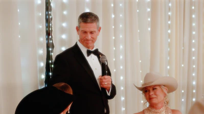 a man in a tuxedo standing next to a woman