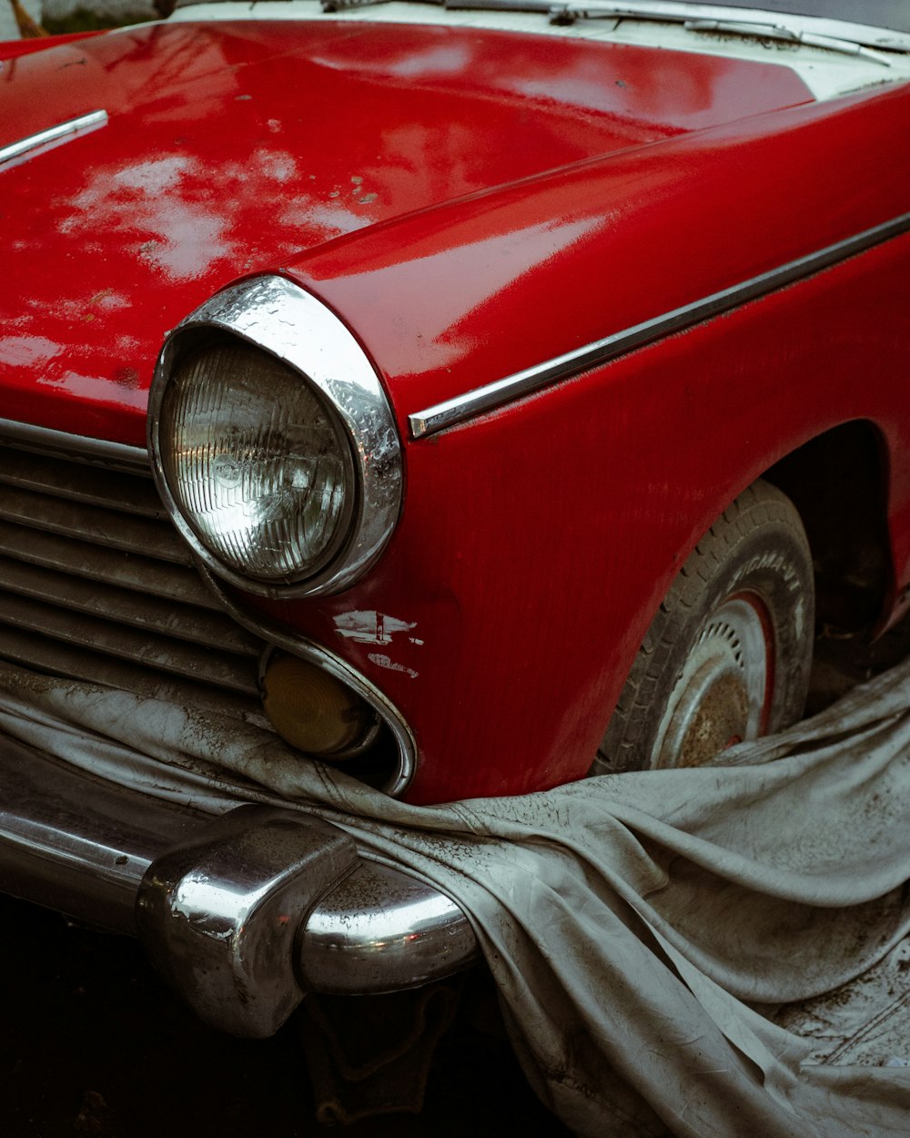 an old red car with a cloth draped around it