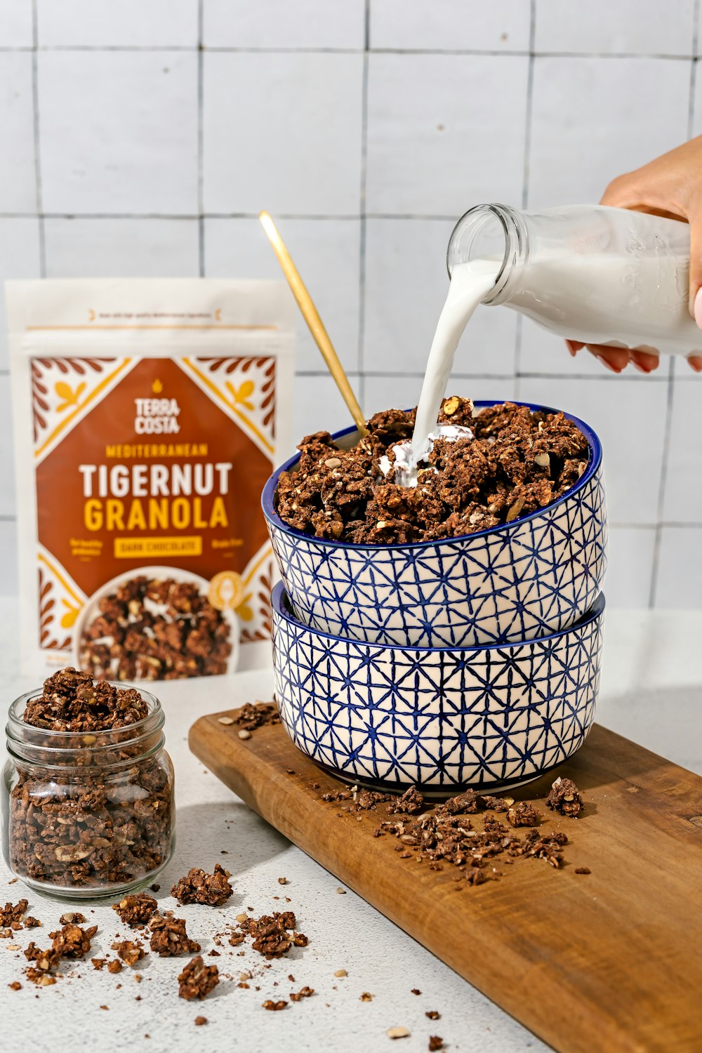 a person pouring milk into a bowl of granola