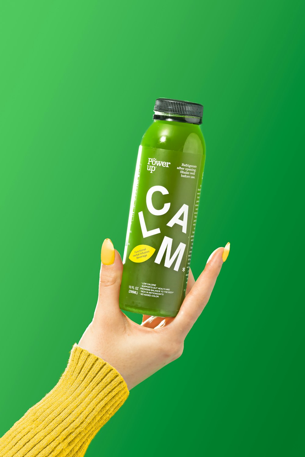 a hand holding a green can of gam on a green background