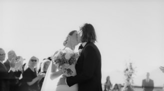 a bride and groom kissing in front of a group of people