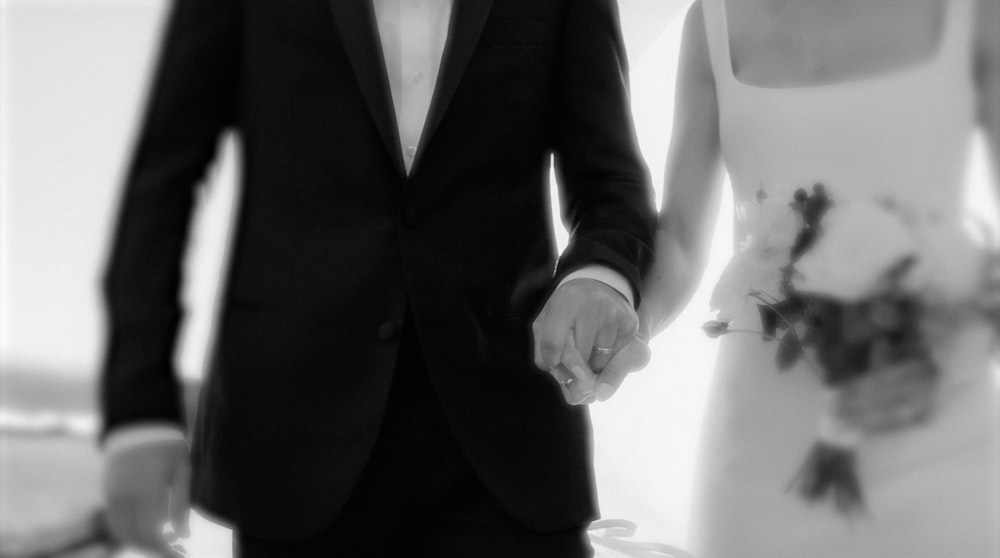 a man and a woman in formal wear holding hands