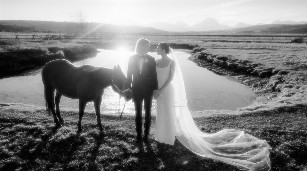 a bride and groom standing next to a horse