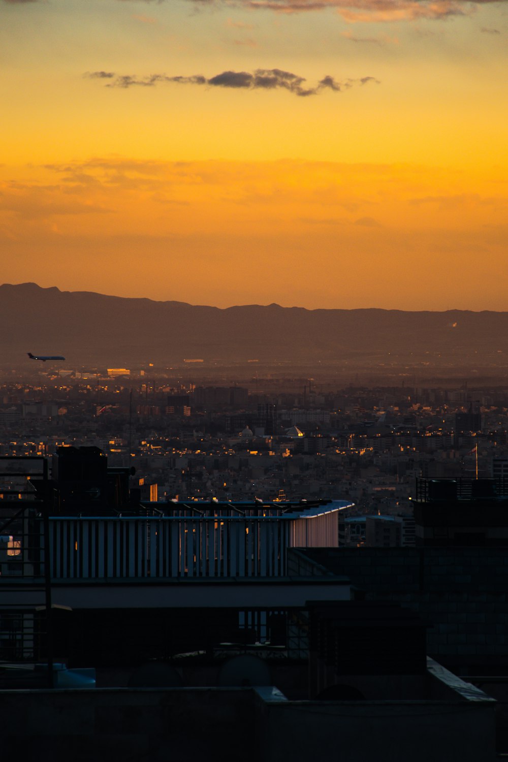 a plane flying over a city at sunset