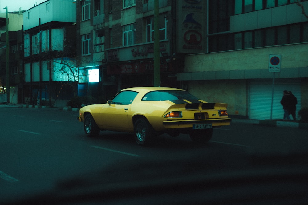 une voiture jaune roulant dans une rue à côté de grands immeubles