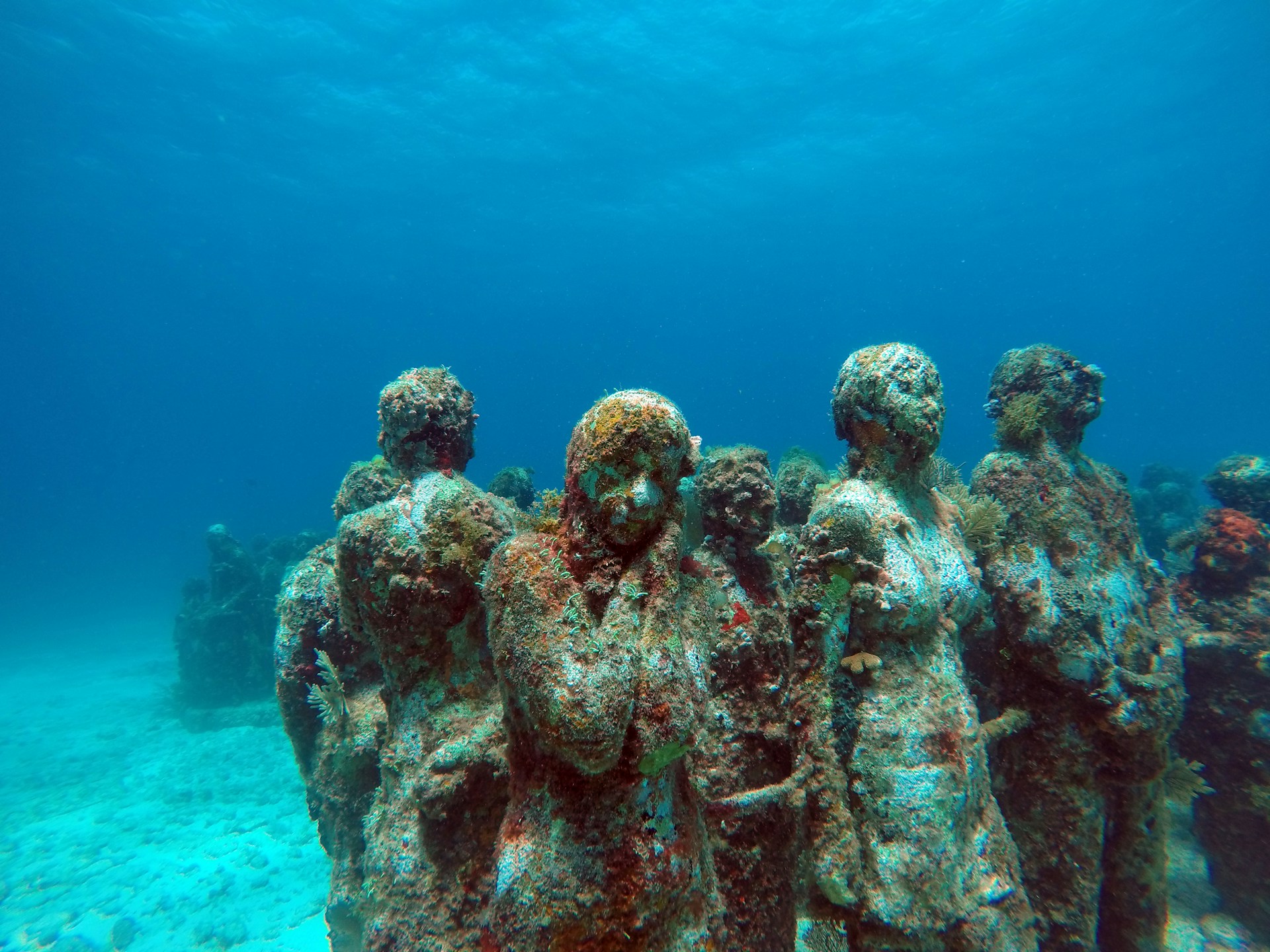 a group of statues sitting on top of a sandy bottom