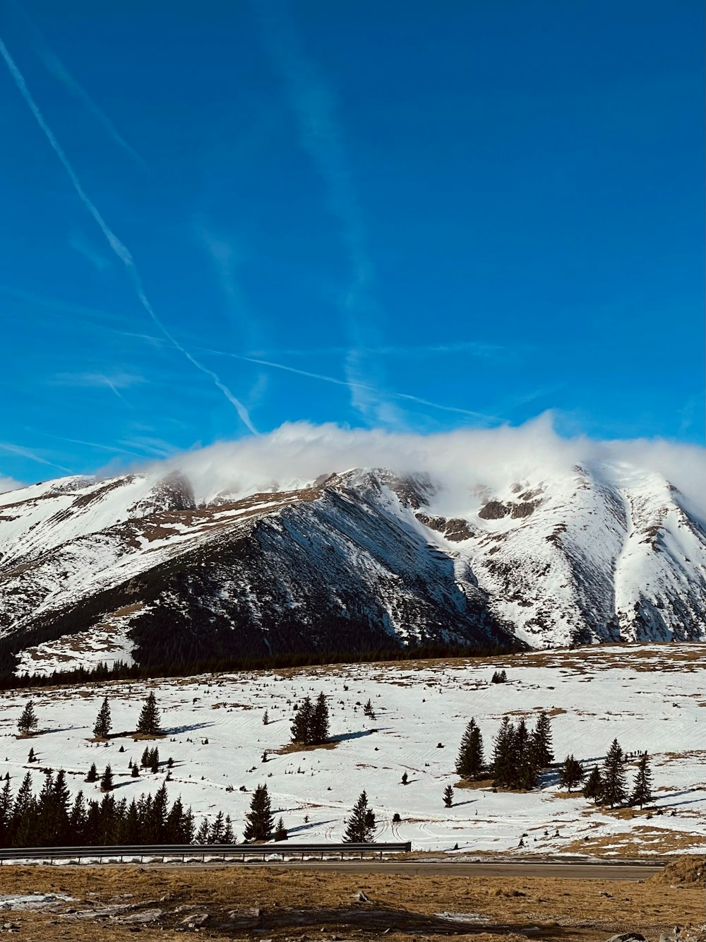 a snow covered mountain range with a few clouds in the sky