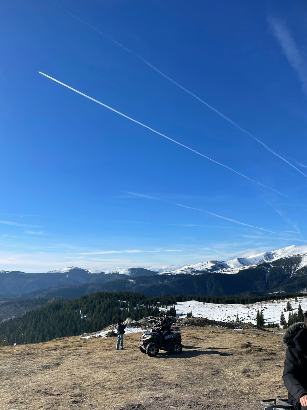 a man standing on top of a hill next to a motorcycle