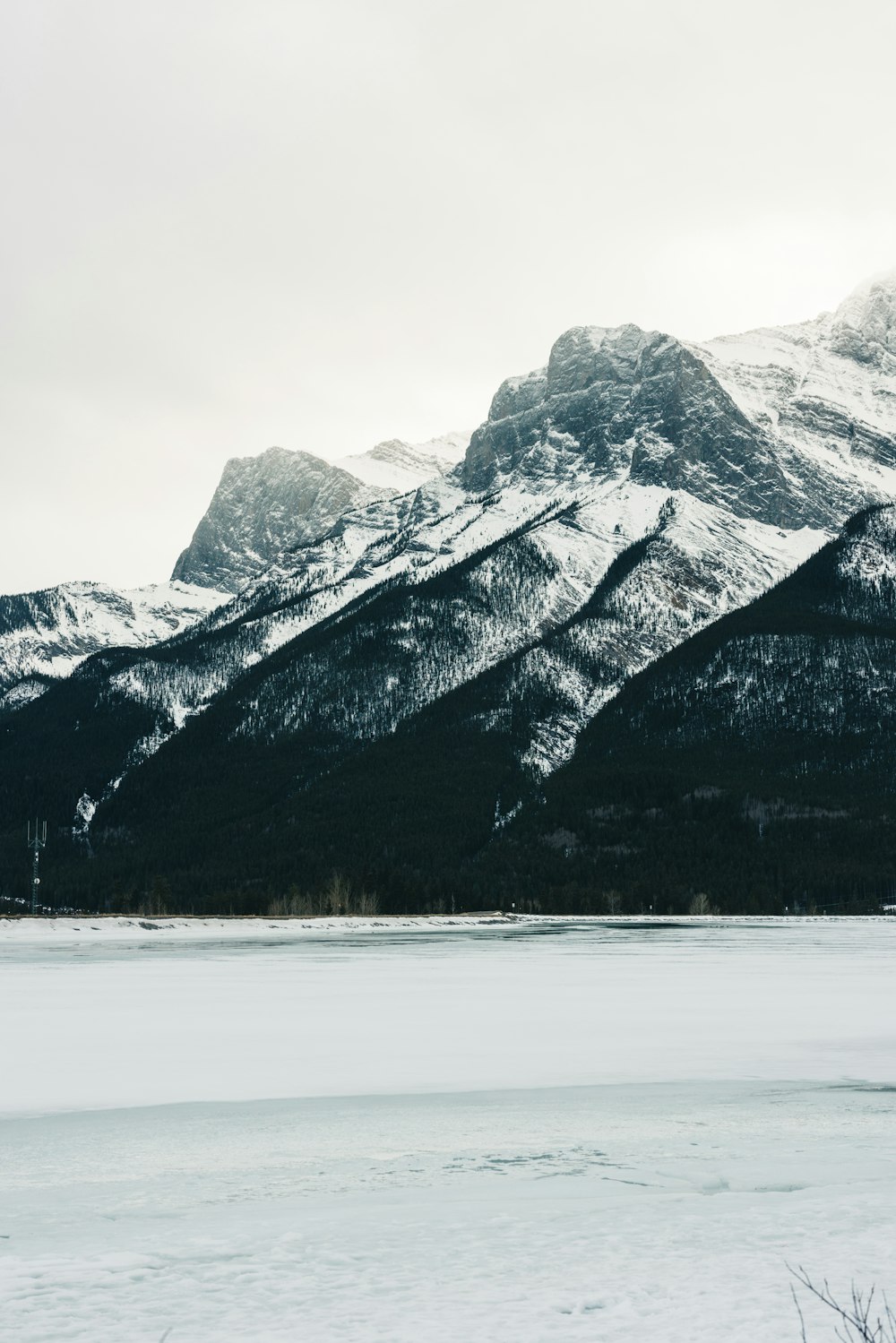 uma cordilheira coberta de neve com um lago em primeiro plano