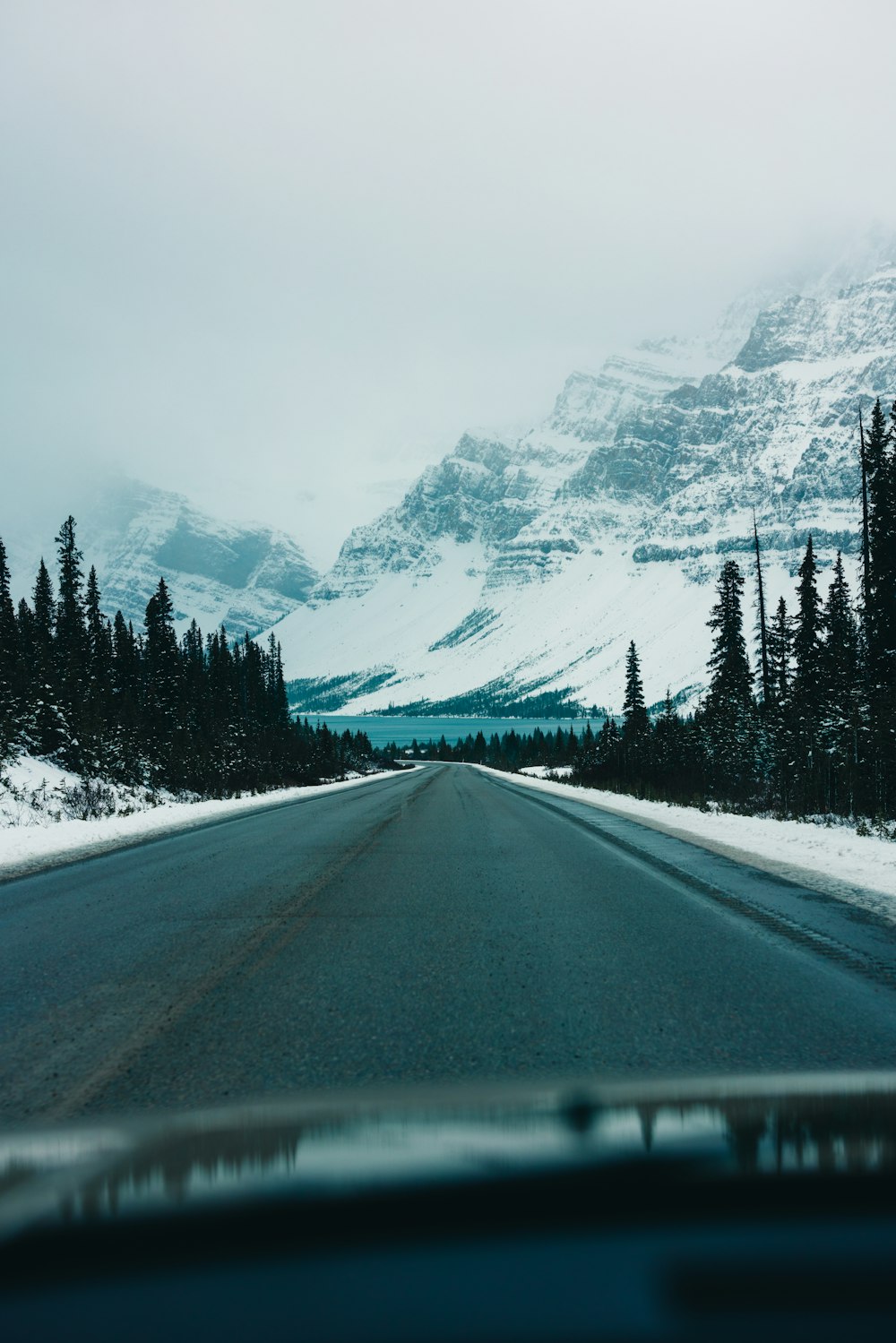 a car driving down a snowy road with a mountain in the background