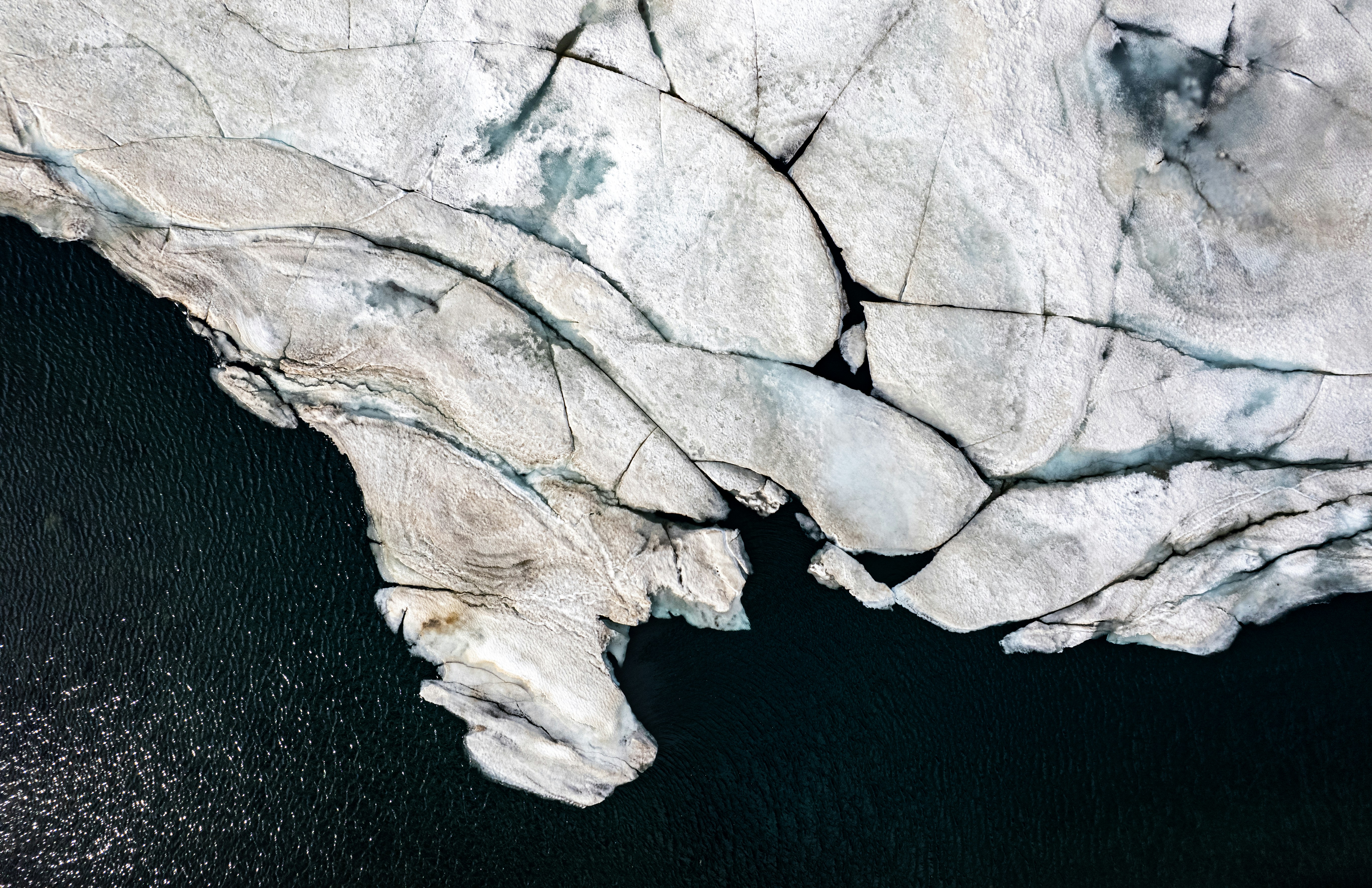an aerial view of an iceberg in the water, An aerial view captures the intricate patterns of a glacier