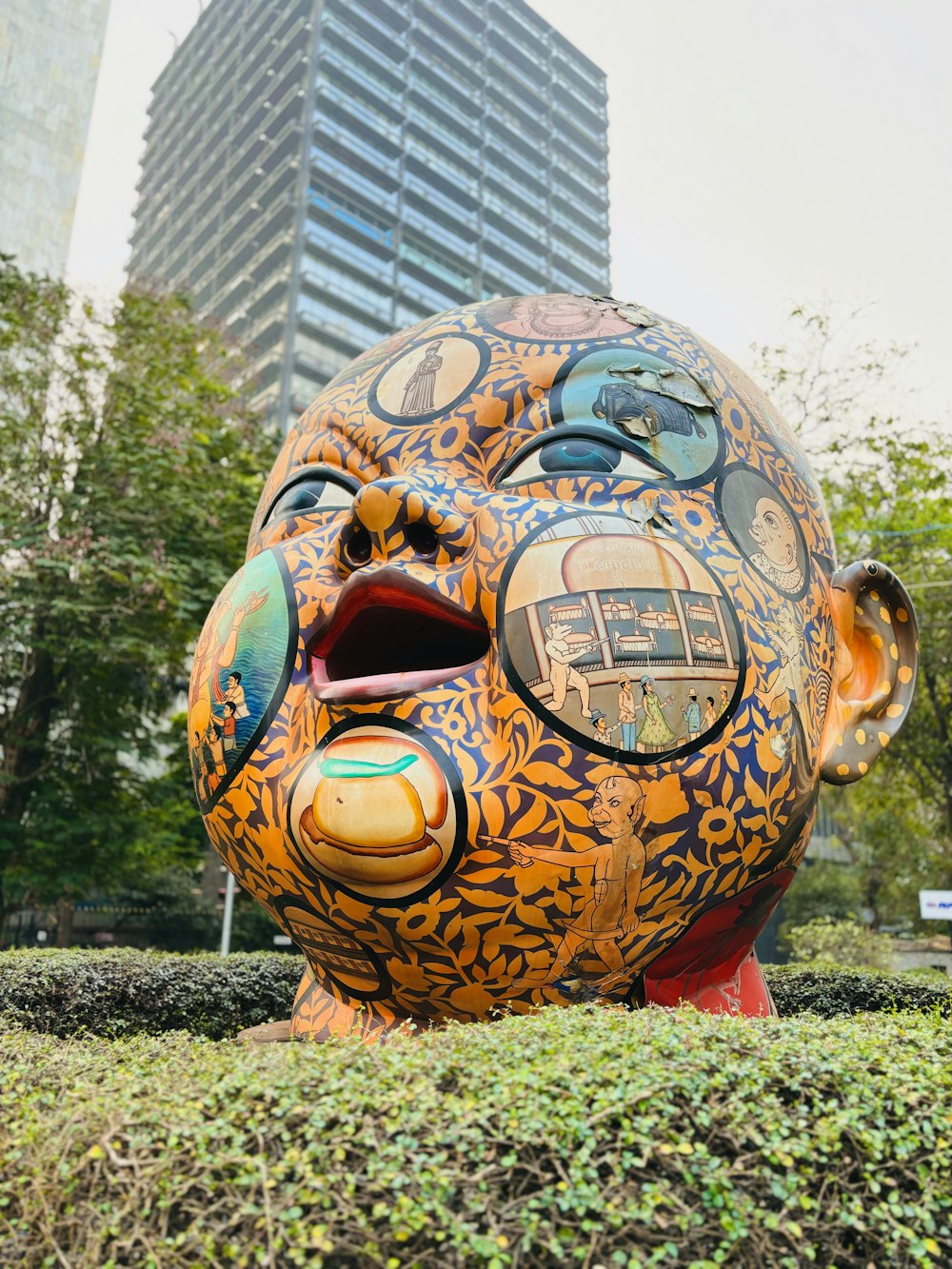 eine Skulptur eines Gesichts mit einem Gebäude im Hintergrund