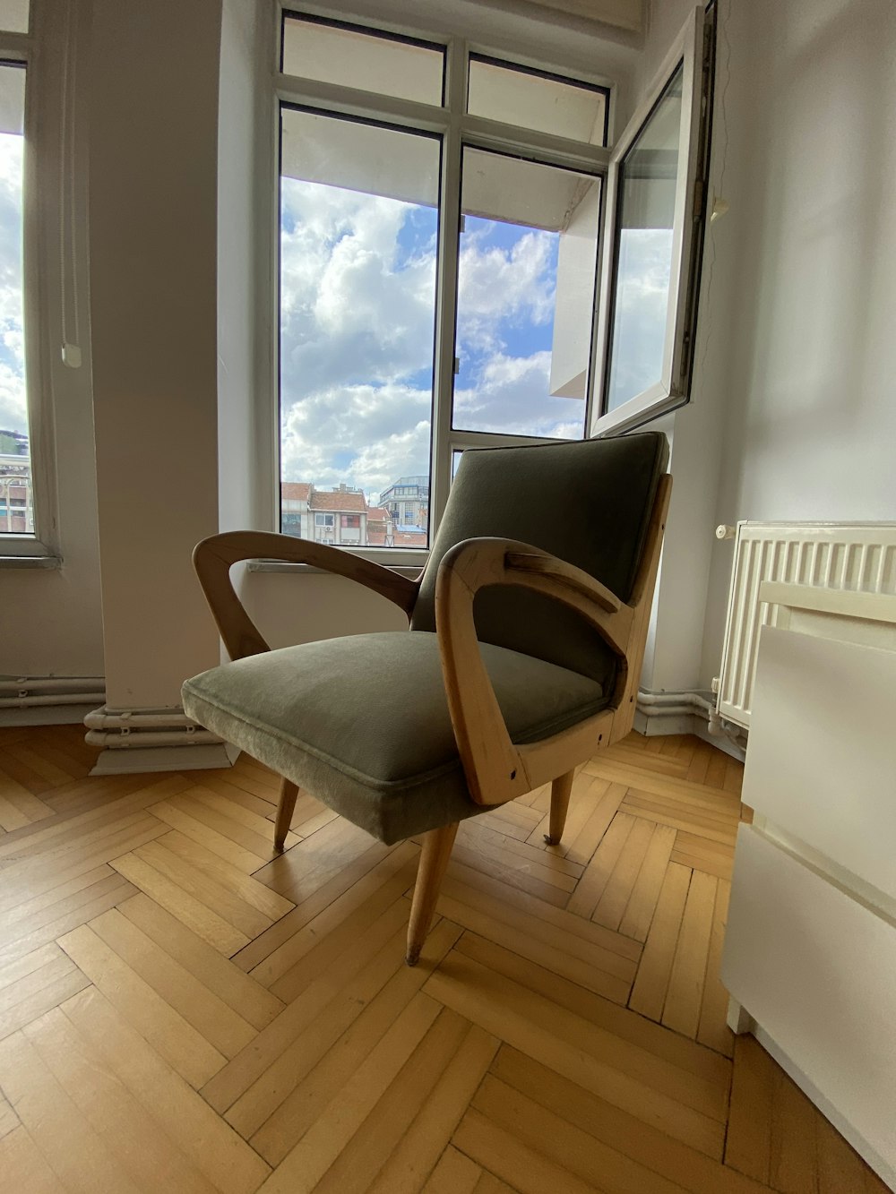 una silla sentada sobre un duro suelo de madera frente a una ventana